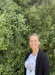 Rachael Koch author in front of green bushes